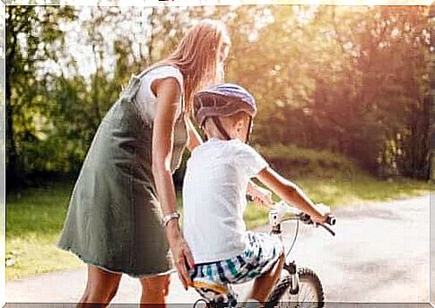 encourages positive behavior: mother helps children ride a bike