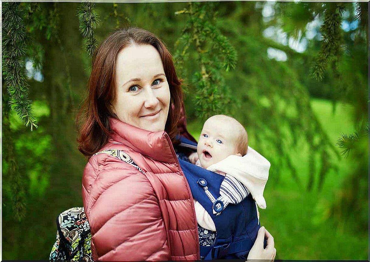 A woman going for a walk with her baby in a baby carrier.