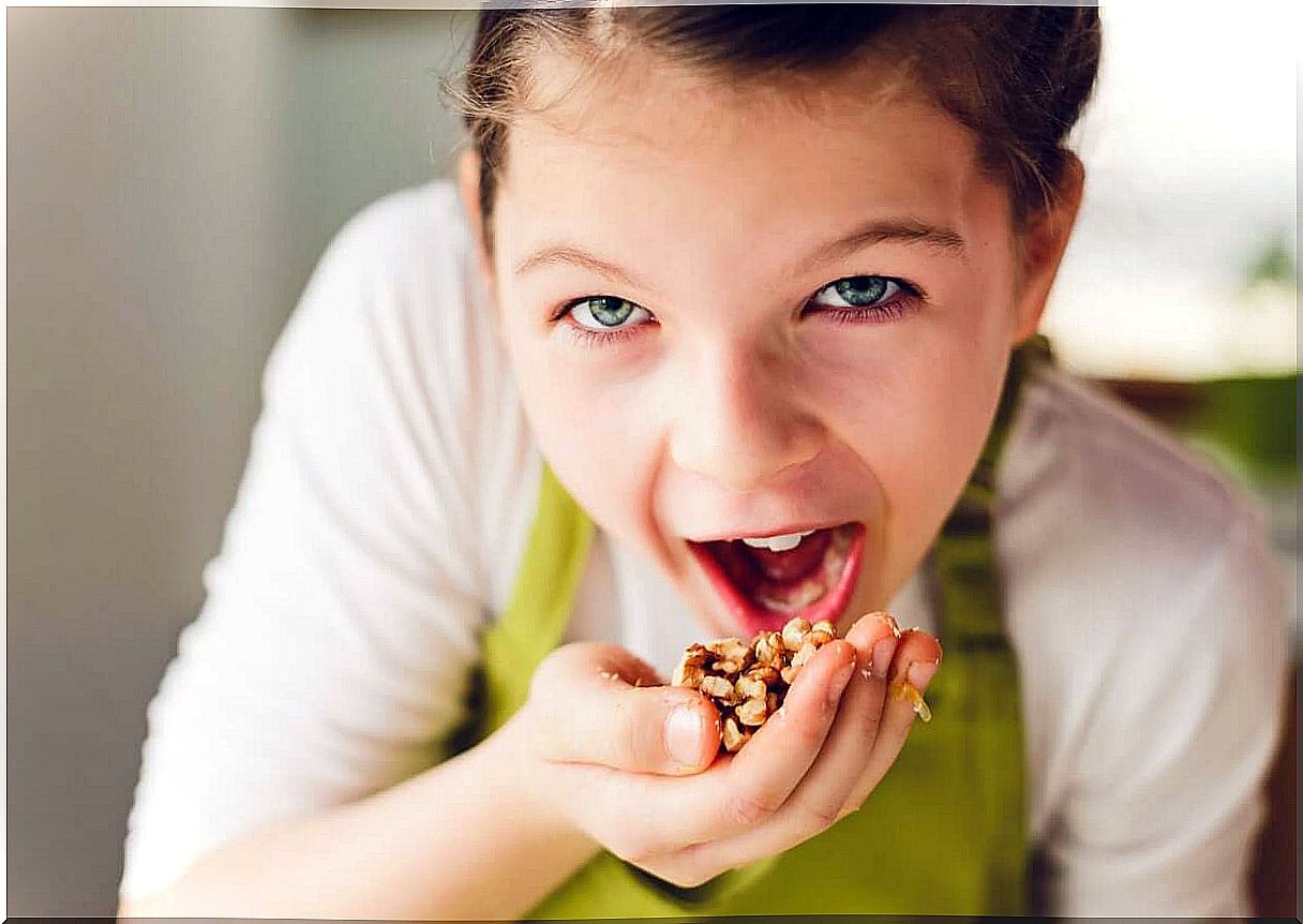 A child putting granola in his mouth.