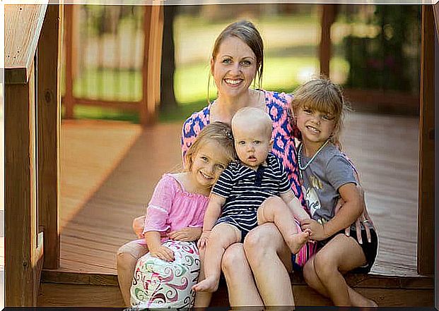 Mom is sitting with three children on the stairs