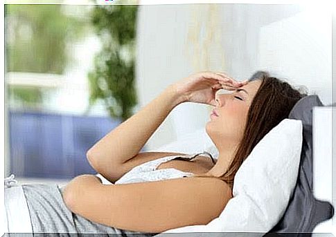 Woman in bed holding her forehead