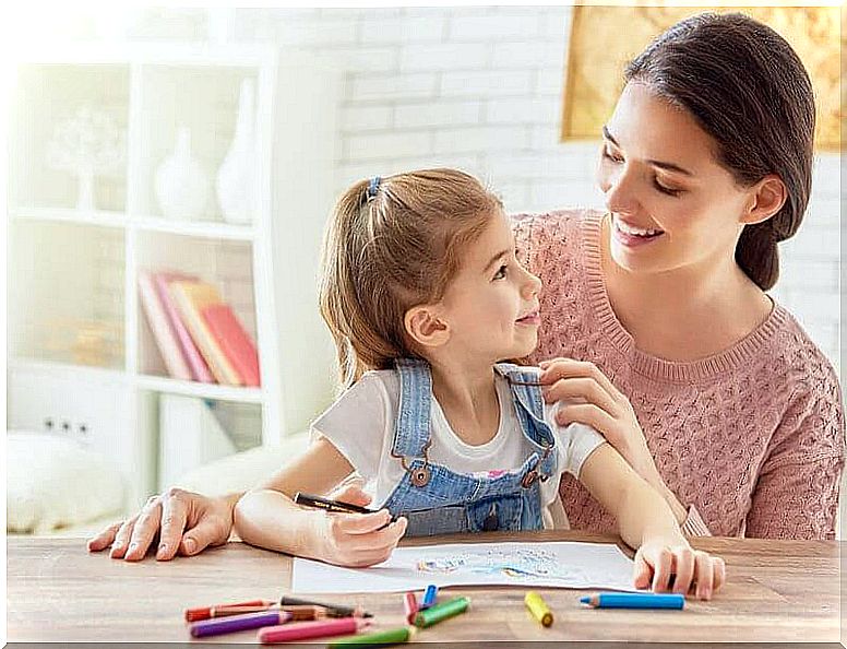 girl draws with crayons and mother watches