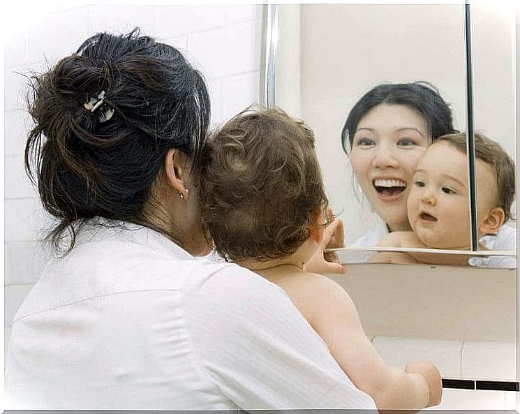 Mom with baby in front of the mirror.