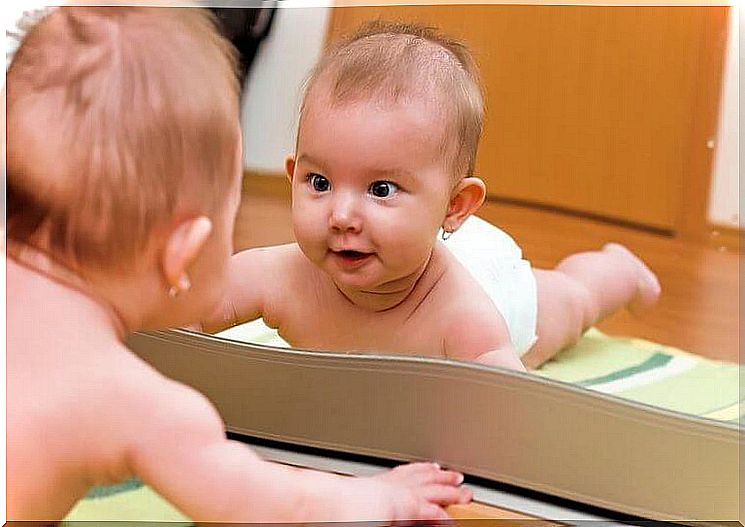 Baby looking surprised in the mirror.