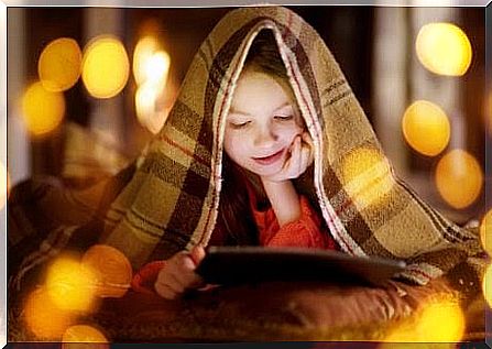 children under blanket watching movie on tablet