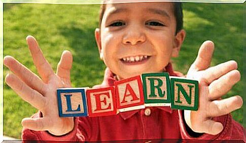 A child holds blocks that form the word "learn".