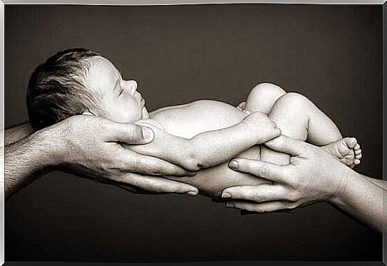 newborn is held up by hands