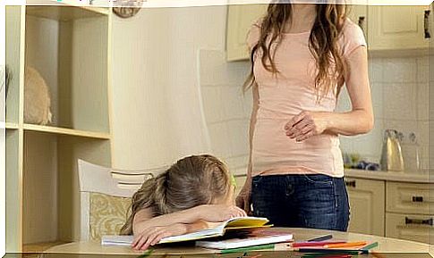 Mother by girl lying over her textbooks