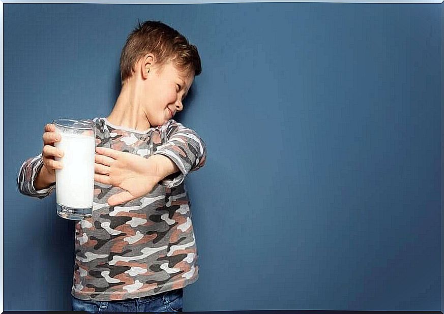 boy holds a glass of milk he does not want