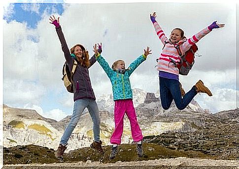 Three girls jump against the background of mountains