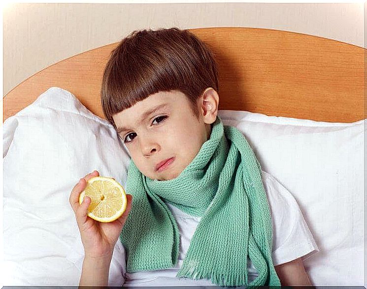 boy with scarf in bed holding up a lemon