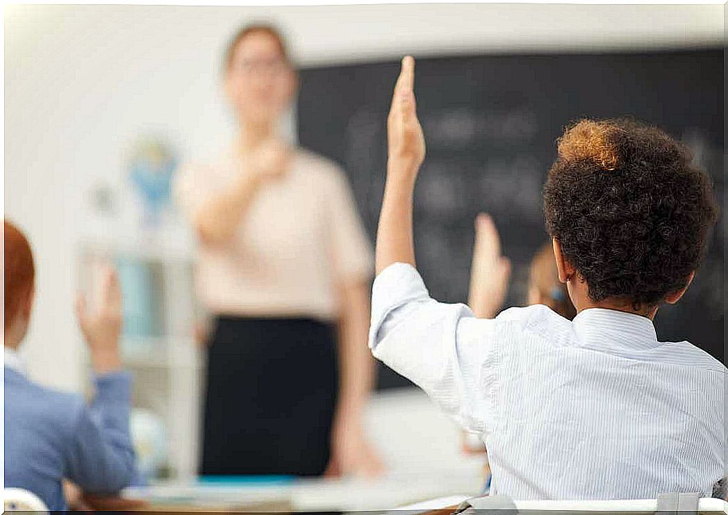 A boy raises his hand in a classroom.