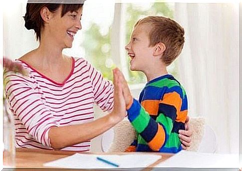 The importance of educating your child: mother and boy do high five over homework