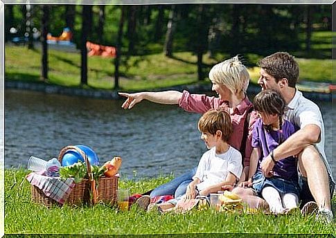 Family sitting on the grass and enjoying a picnic.