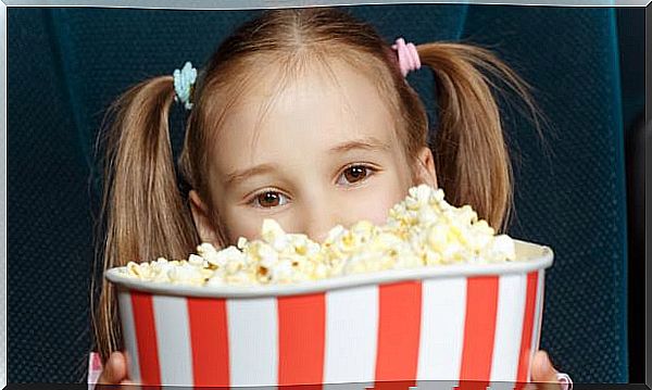 Children look forward behind the popcorn container.