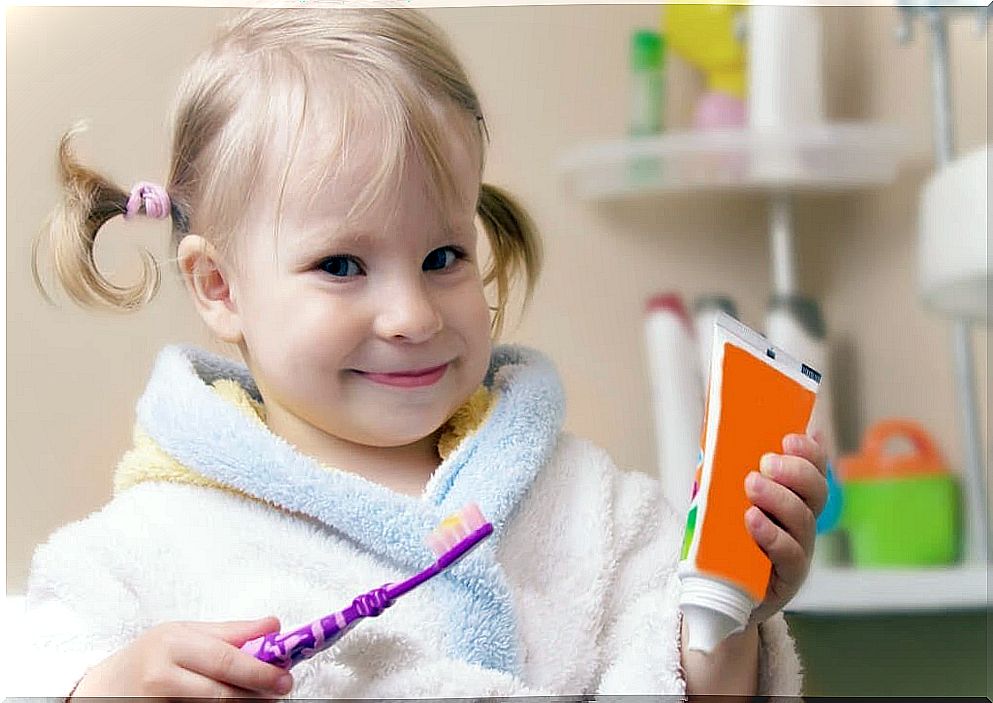 little girl with toothbrush and toothpaste tube