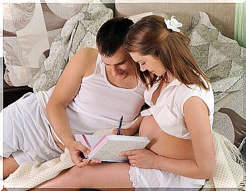 man and pregnant woman writing in book