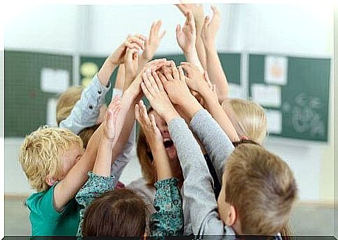 Children with their hands up around a happy teacher