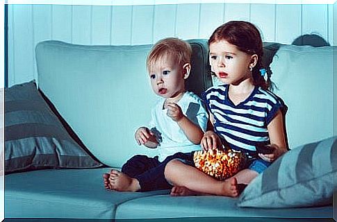 Two small children in TV sofa with popcorn