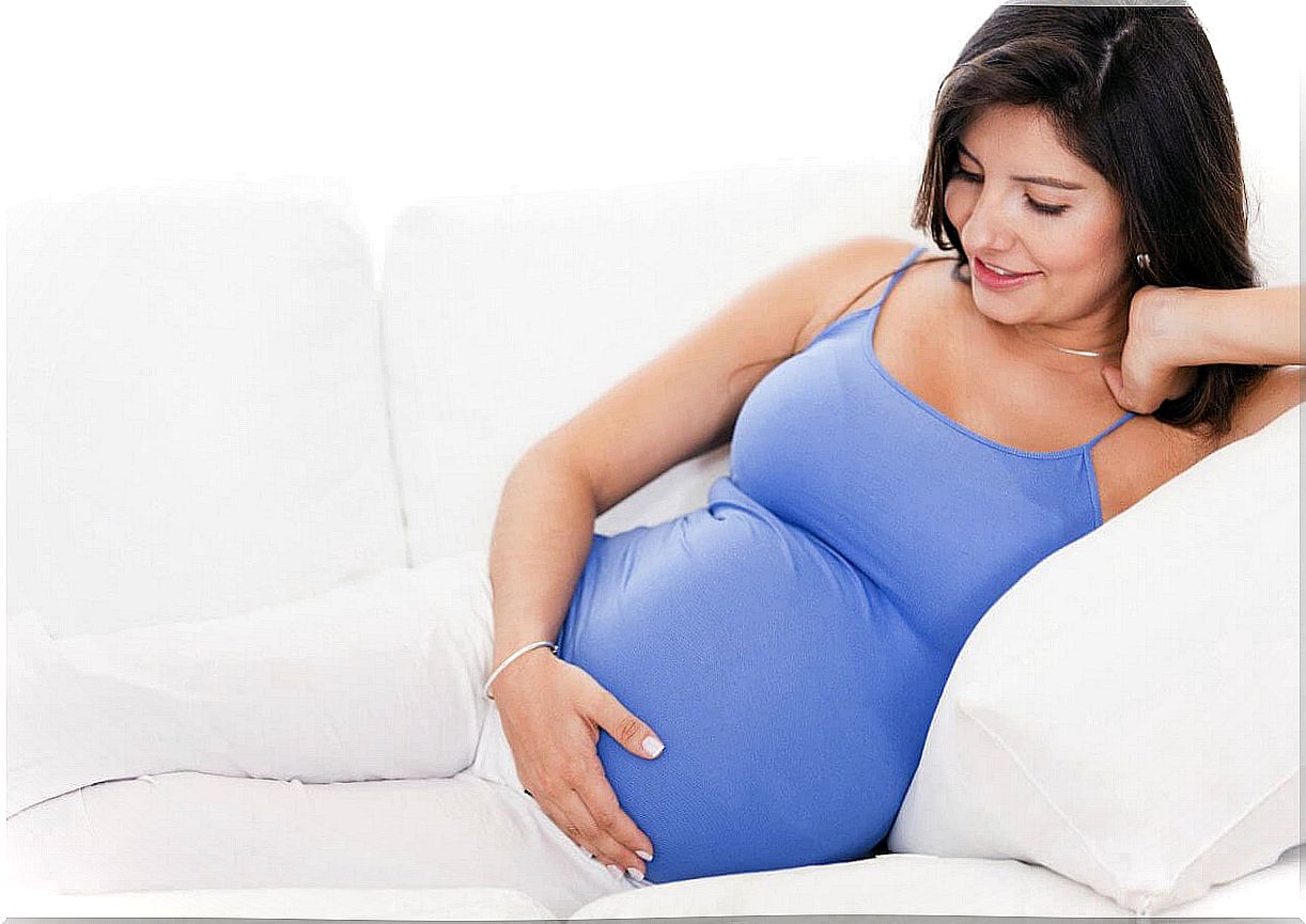 pregnant woman on sofa with hand on belly