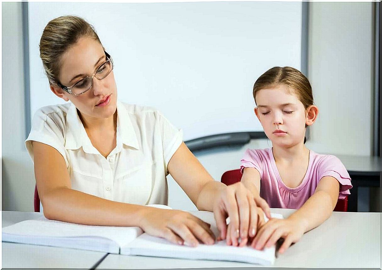 A teacher helping a young girl read Braille.