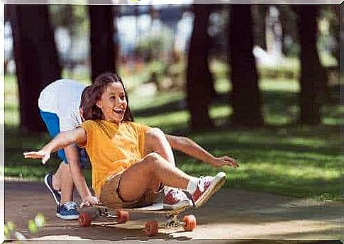 Siblings play with a skateboard.