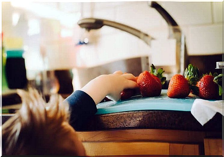 children take strawberries from a cutting board