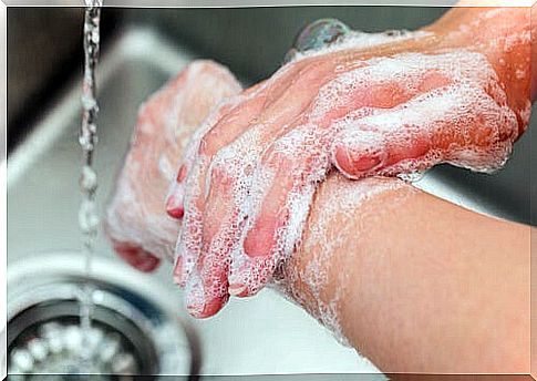 Hands with soap suds approach water jet