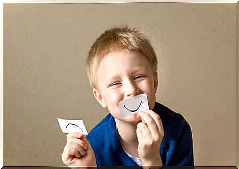 The importance of building resilience in children: boy holds note with happy mouth in front of face