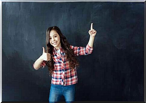 The importance of building resilience in children: girl makes thumbs up in front of blackboard