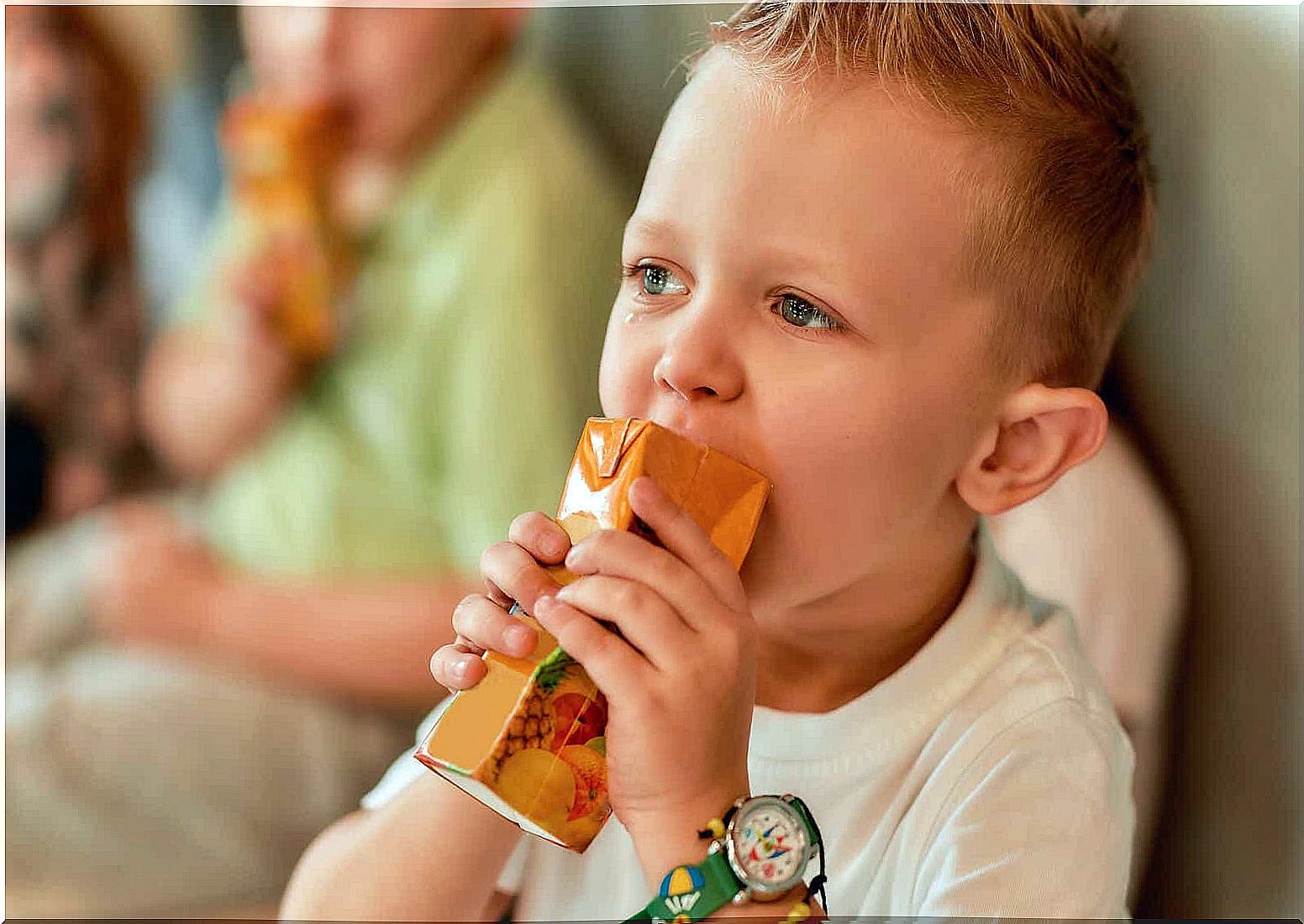 A crying boy comforts himself with juice.