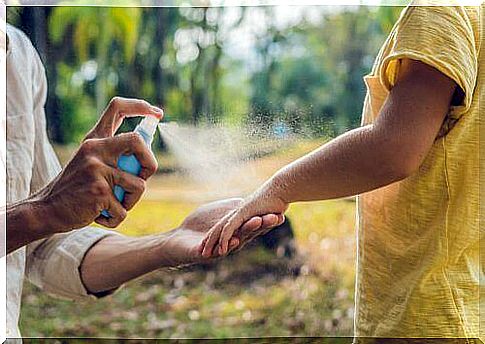 Mother sprays insect spray on her baby's arm.