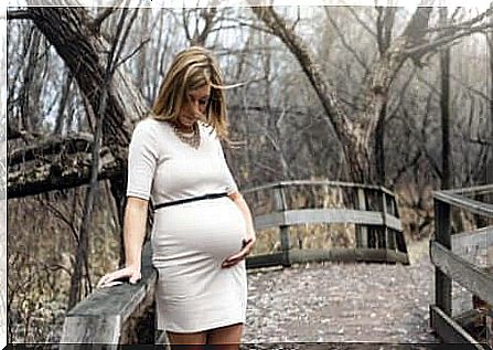 Winter clothes for pregnant women: A pregnant woman on a bridge.